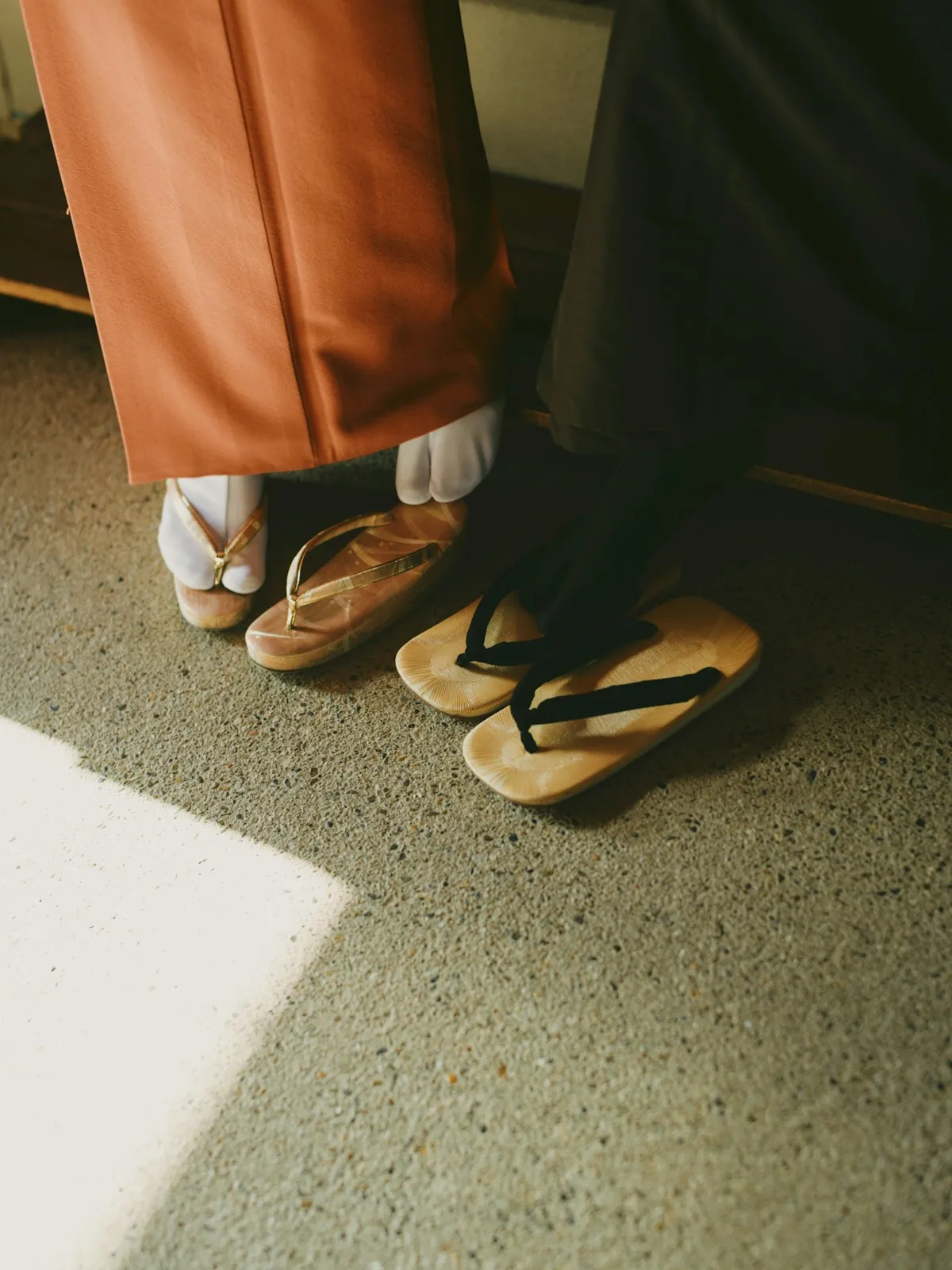 Two pairs of zori sandals and white tabi socks peeking out from beneath kimono hems